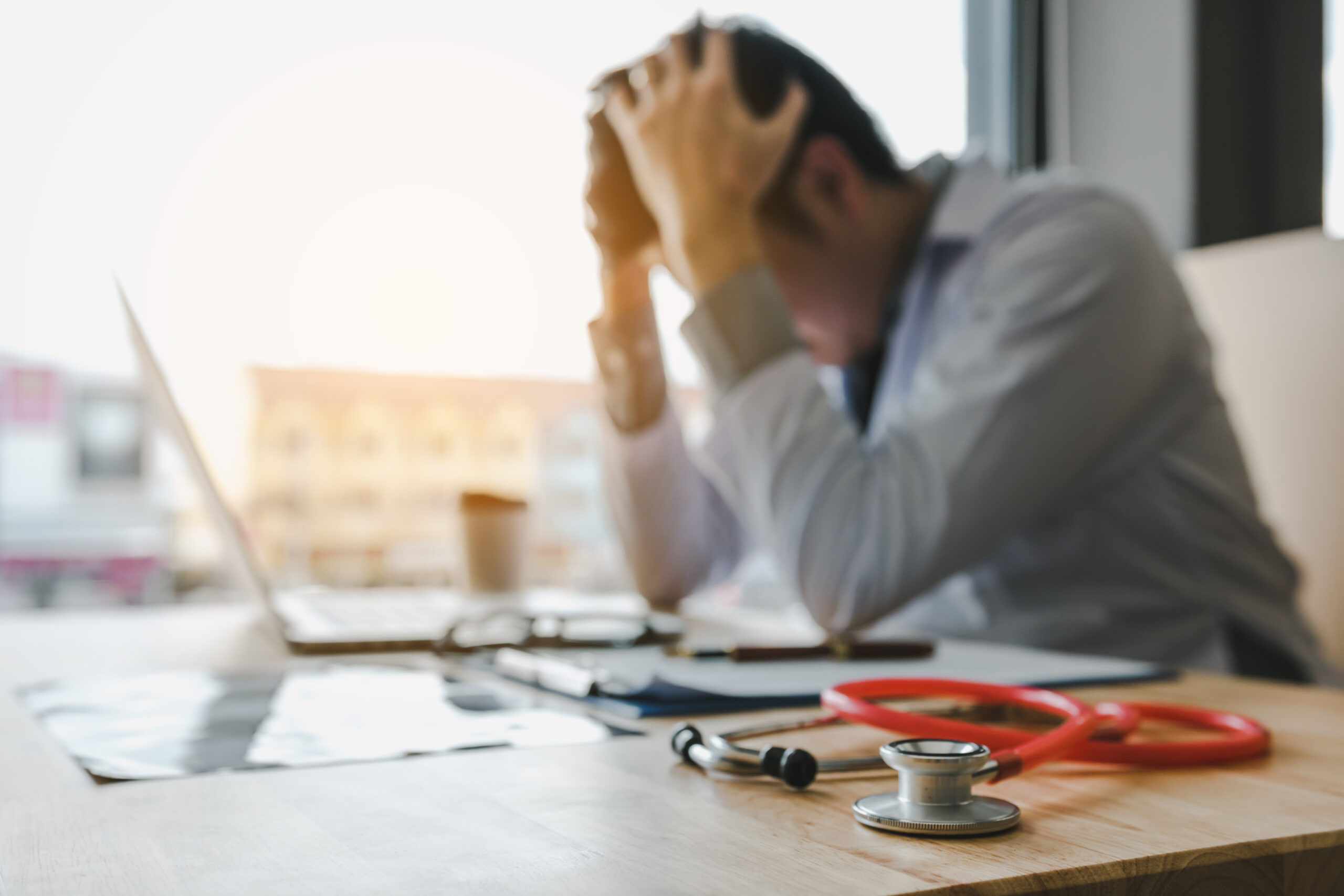 Doctor being exhausted in the office with head in hands.